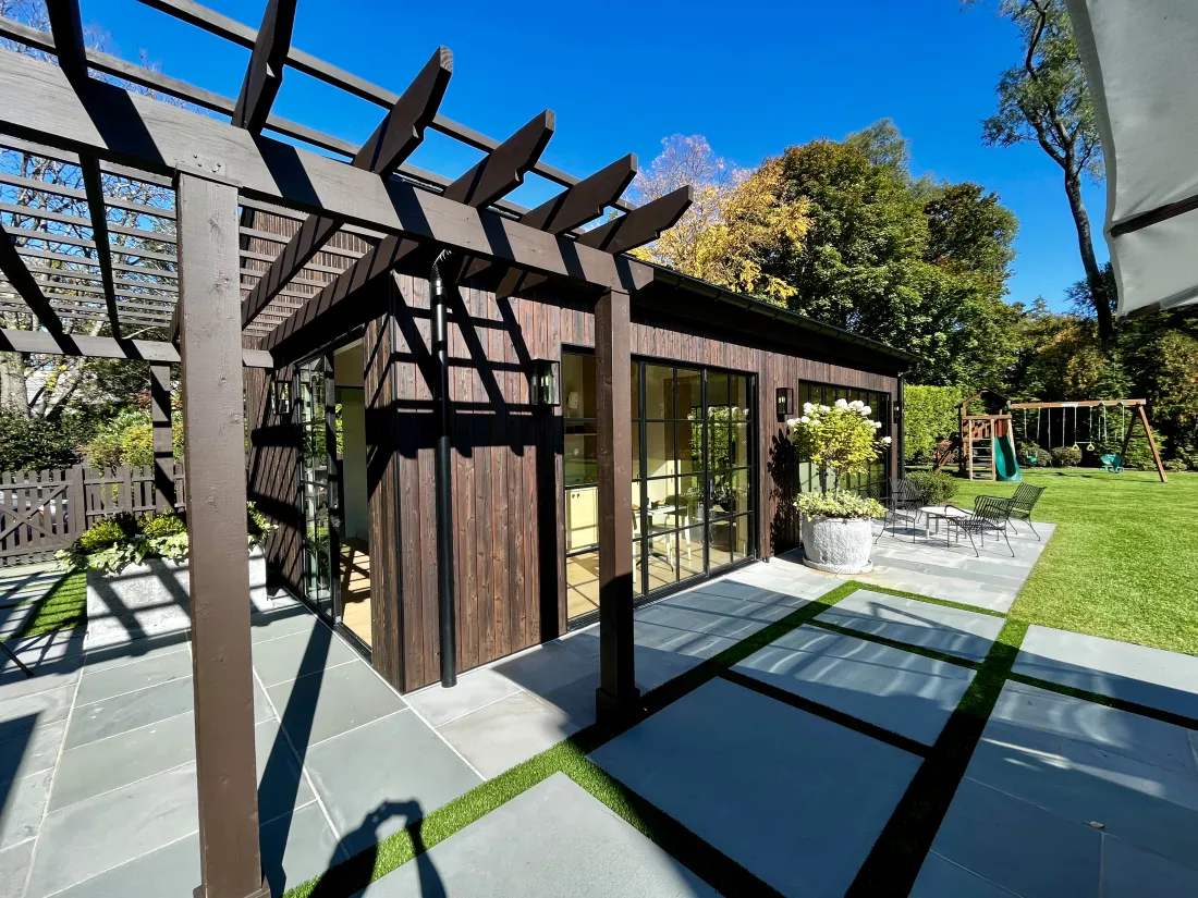 Pool house exterior with timber pergola, bluestone terrace and lawn