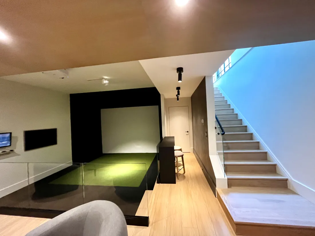 Golf simulator and recreation room beside the stair