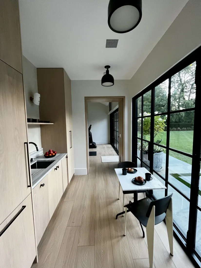 Kitchenette with light oak cabinets and a wall of black-framed windows