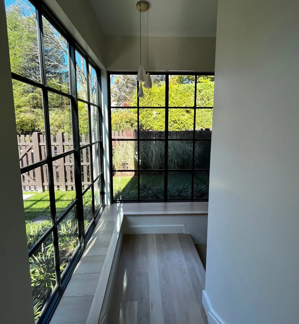 Stair landing wrapped in black steel windows overlooking the garden