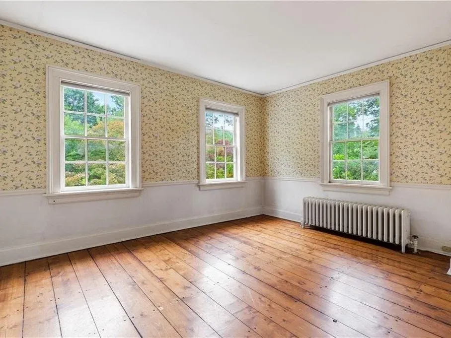 Bedroom with wallpaper and wide-plank floors