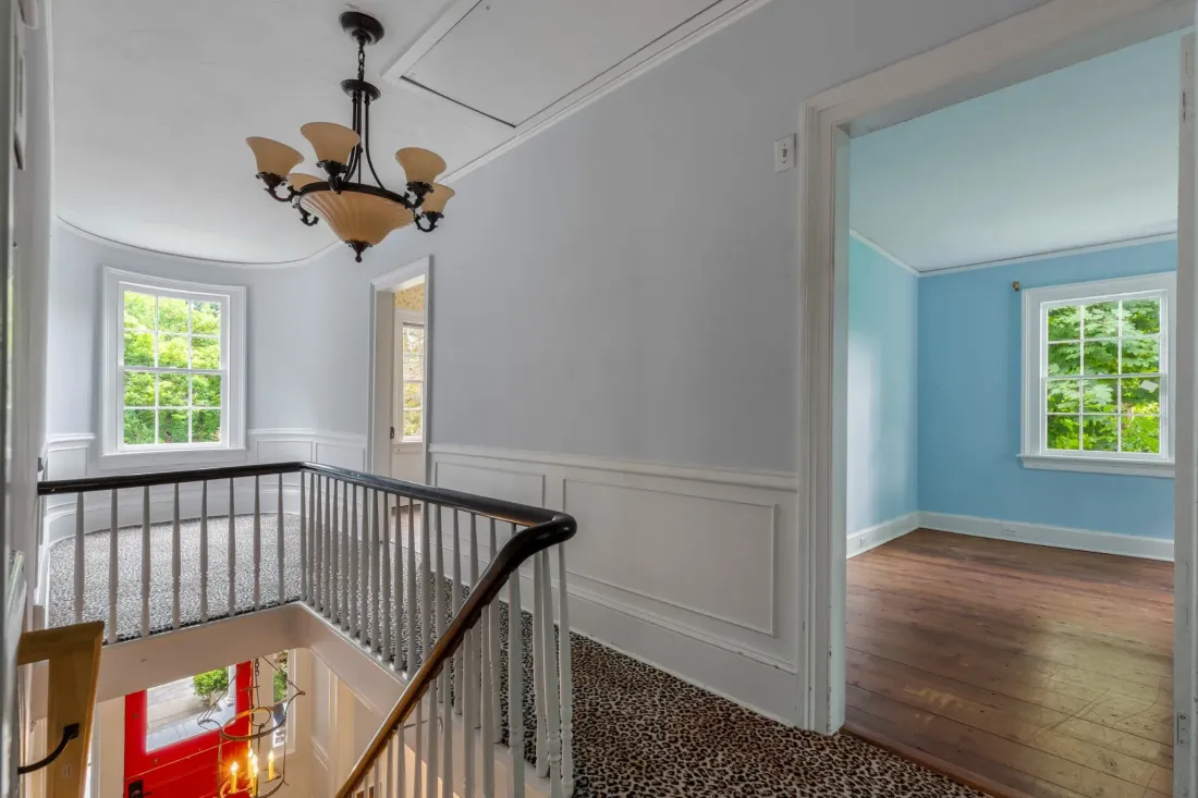 Upstairs landing with a stair railing and chandelier