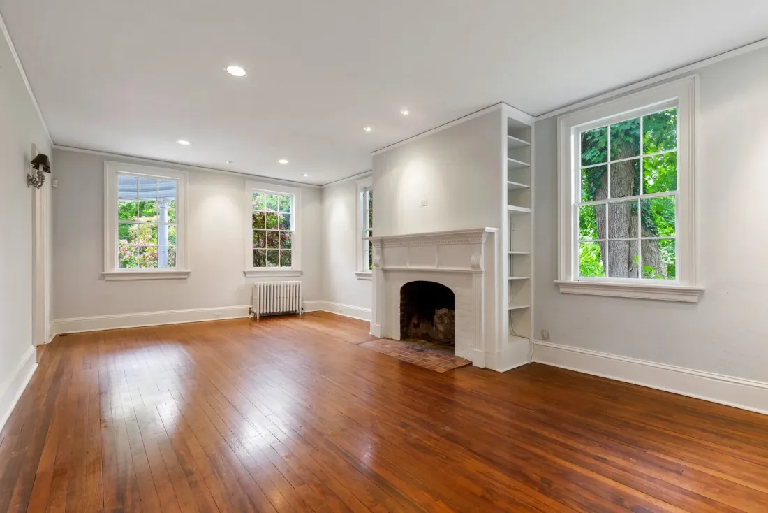 Living room with a white mantel fireplace, built-in shelves and wood floors