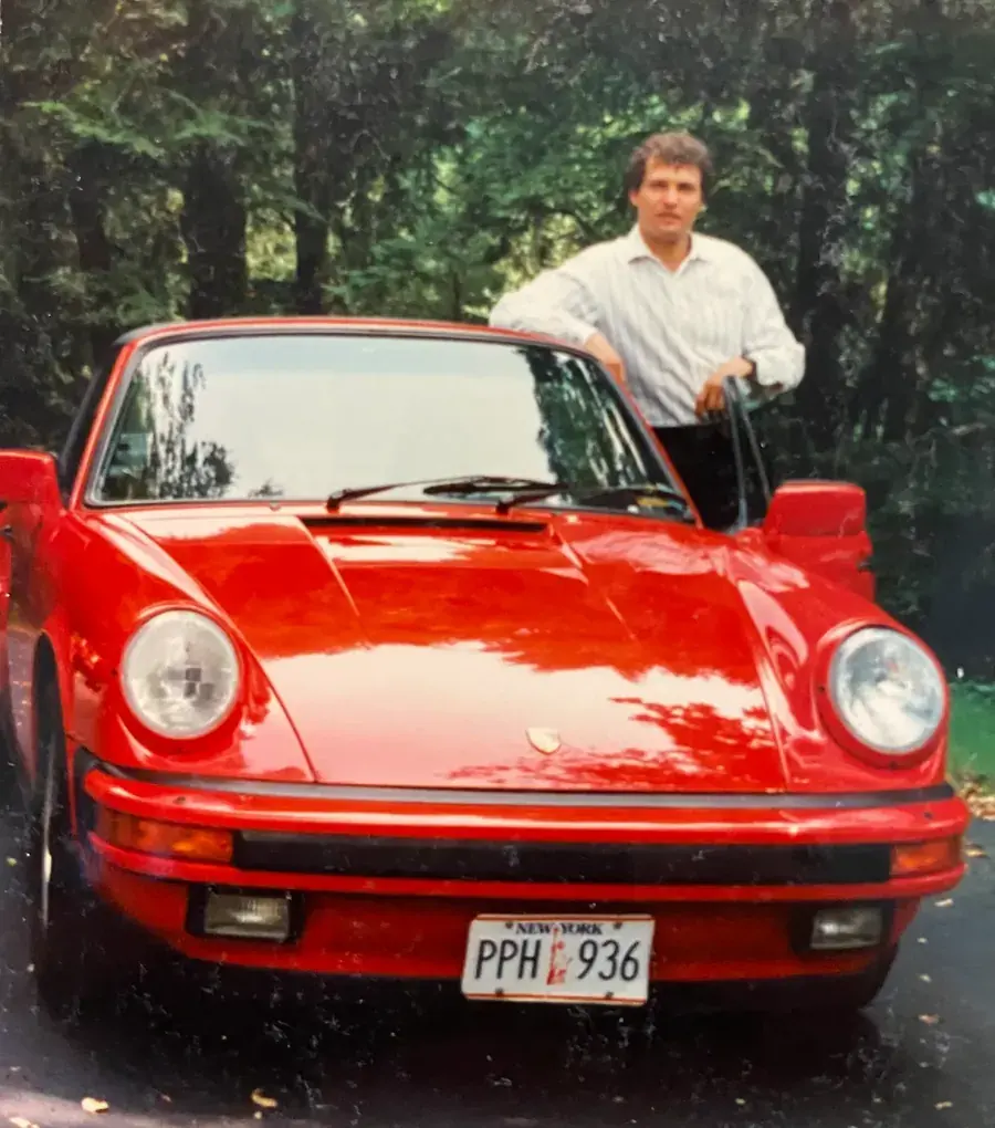 Kip Konigsberg standing beside a red Porsche