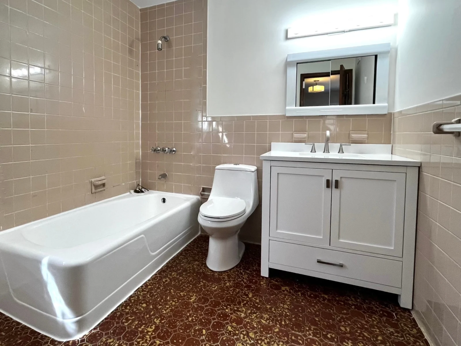 Bathroom after: new vanity, toilet, mirror and light, with the tub and walls refreshed