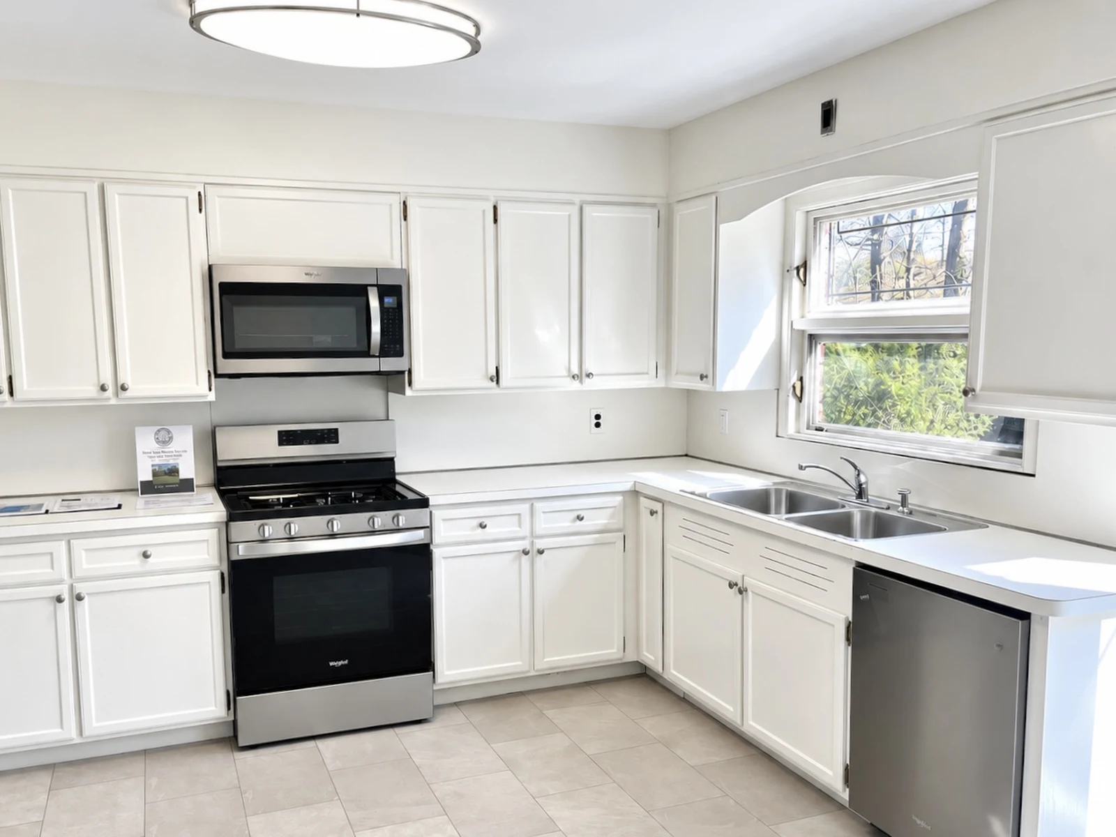 Kitchen after: repainted white cabinets, new hardware, stainless appliances and new luxury vinyl flooring