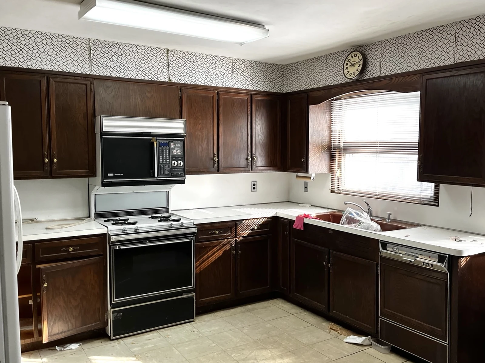 Kitchen before: dark wood cabinets, dated appliances and worn vinyl floor